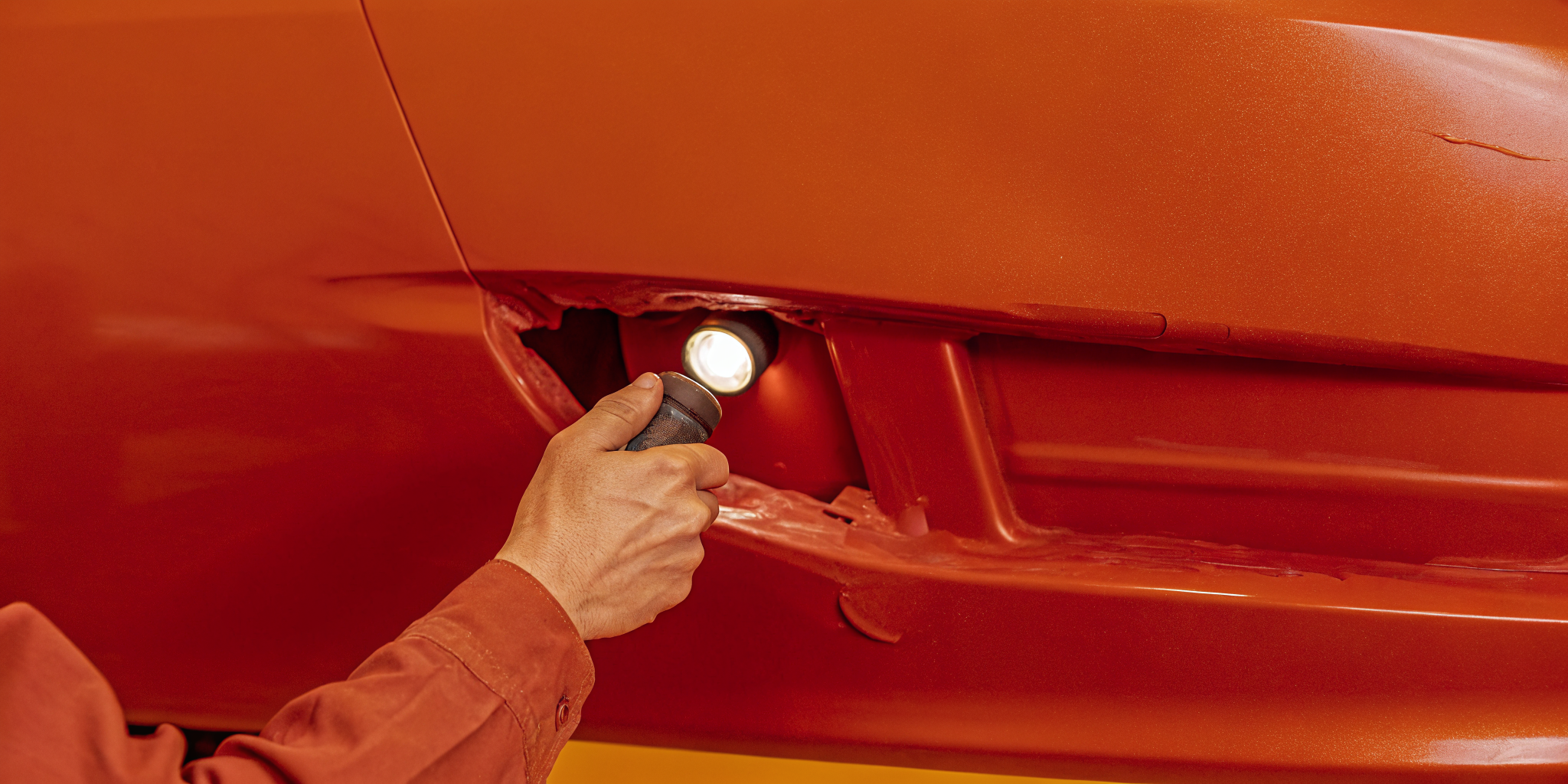 Technician examining bumper damage on a vehicle at an Orlando auto body shop