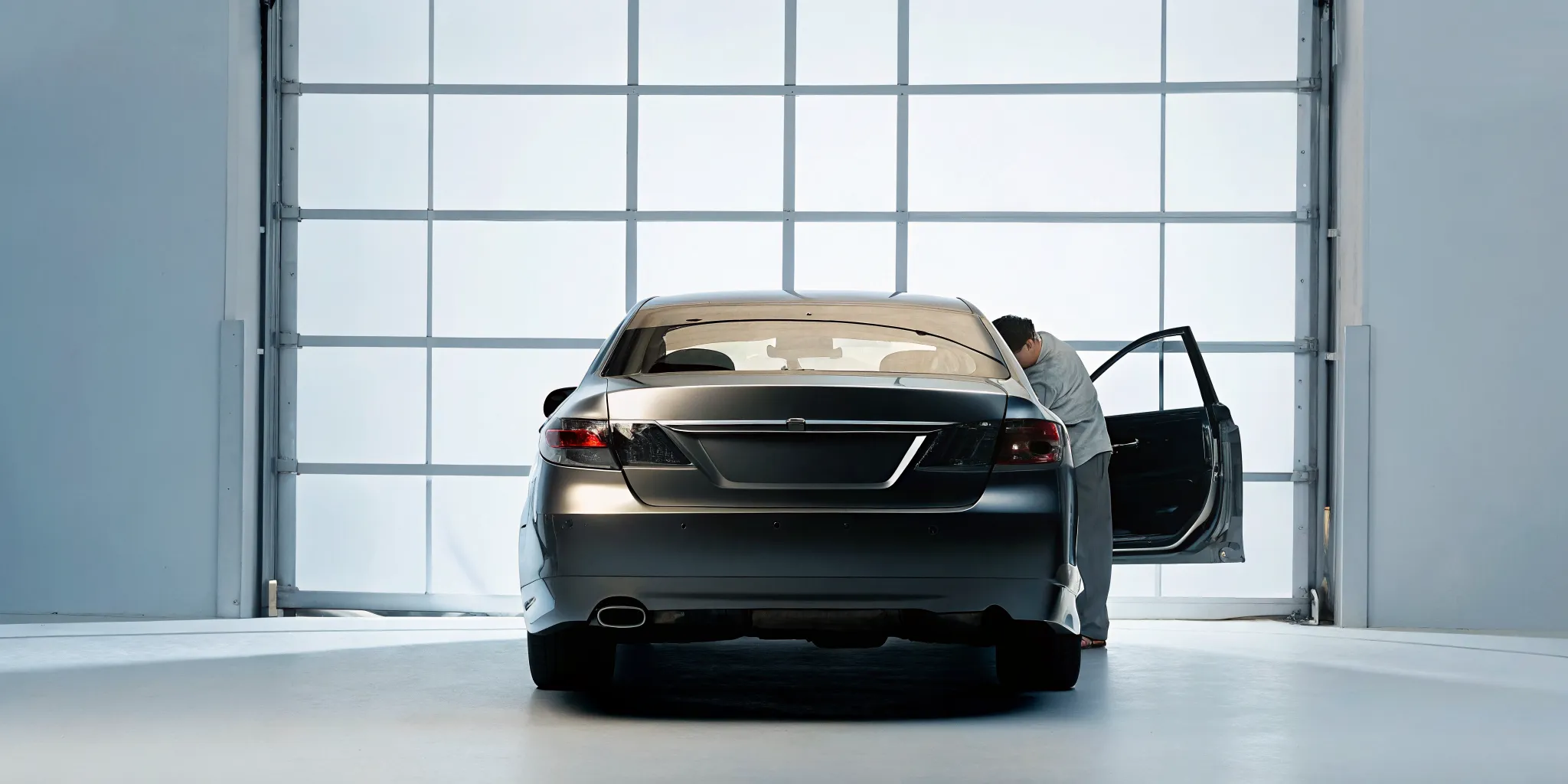 Technician inspecting hidden collision damage on a sedan