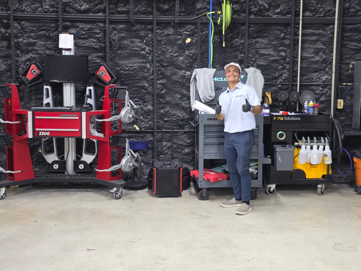 A uniformed Collision Center Orlando technician with wheel alignment and precision measuring equipment A uniformed Collision Center Orlando technician with wheel alignment and precision measuring equipment